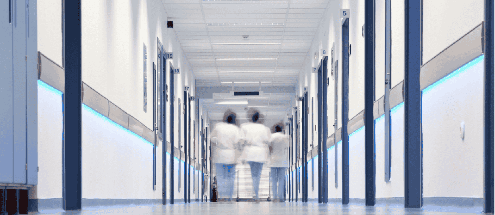 Drei Pflegerinnen laufen Krankenhausgang entland
