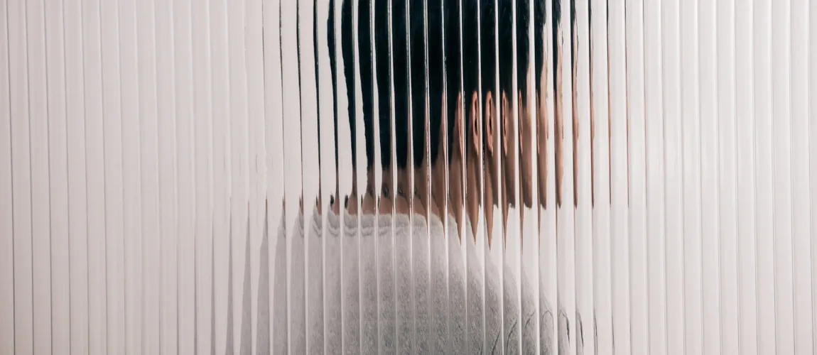 Ein Mann sitzt hinter einer undurchsichtigen Glasfassade.