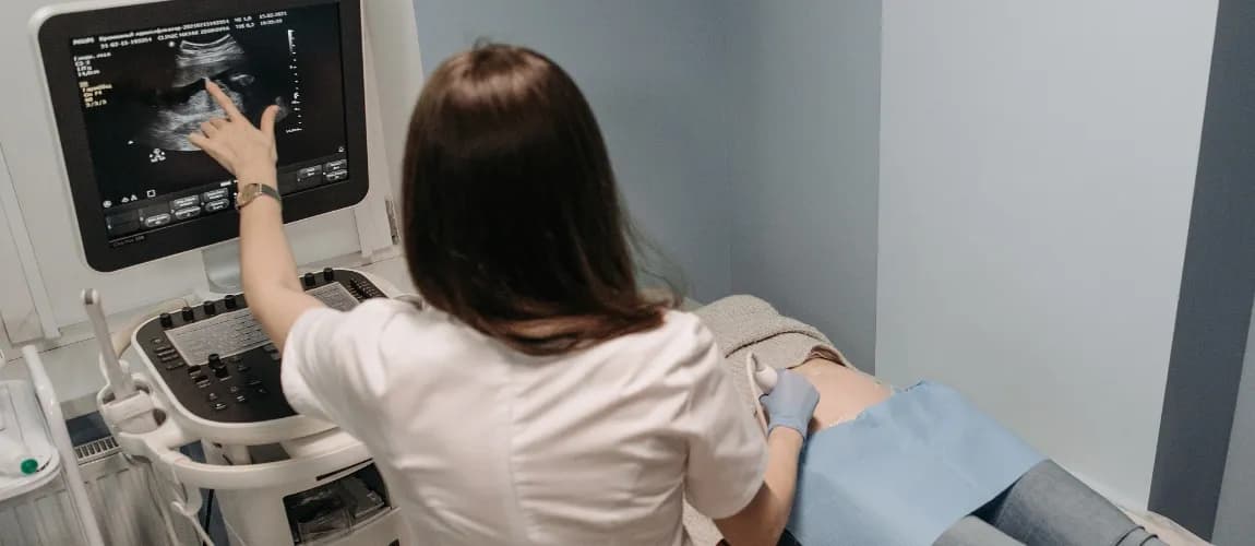 Eine Ärztin untersucht den Bauch einer Frau mit einem Ultraschallgerät.