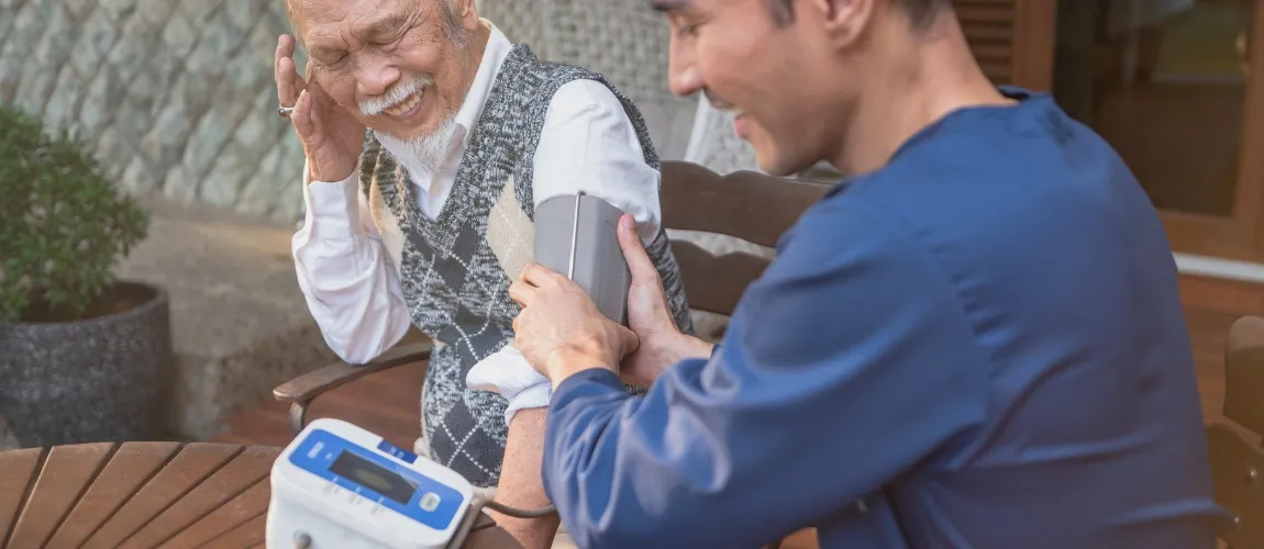 Eine Pflegefachkraft misst bei einem Senioren den Blutdruck.