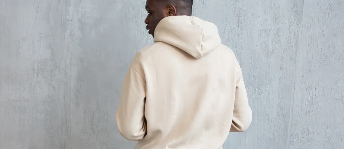 Ein Mann in einem weißen Pullover steht mit dem Rücken zur Kamera.