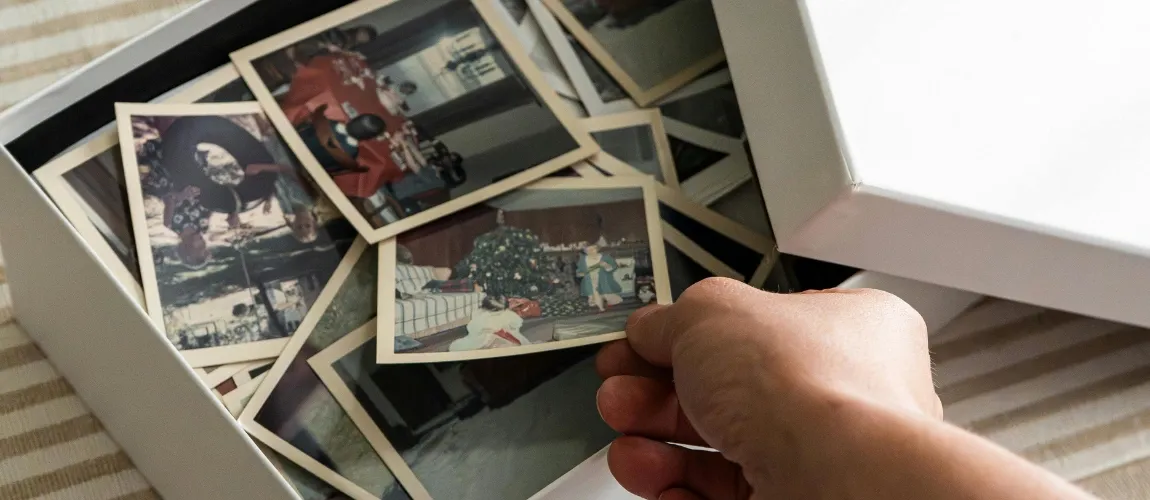 Eine Hand greift in eine Kiste mit Fotos.