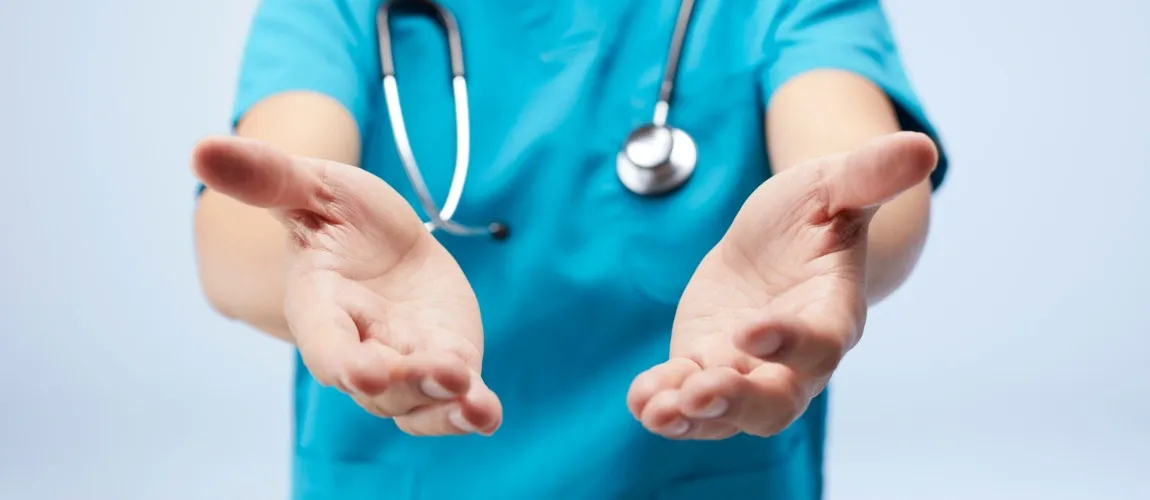 Ein Mann in Pflegekleidung streckt die Hände in die Kamera.