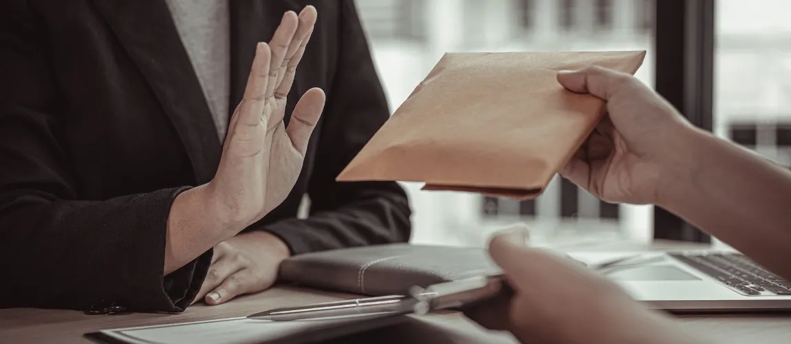 Eine Person reicht einer anderen einen Umschlag, die lehnt ab.