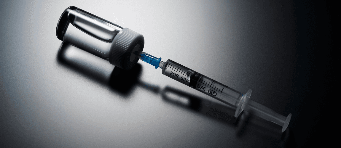 Abbildung einer Spritze, die in einem Behälter steckt. 