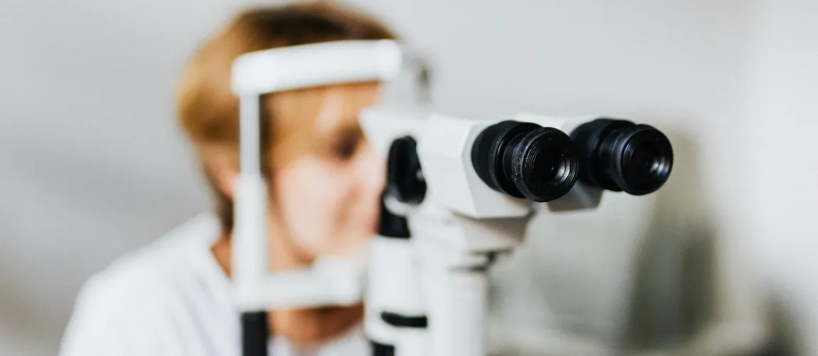 Eine Frau sitzt vor einem Untersuchungsgerät für die Augen.