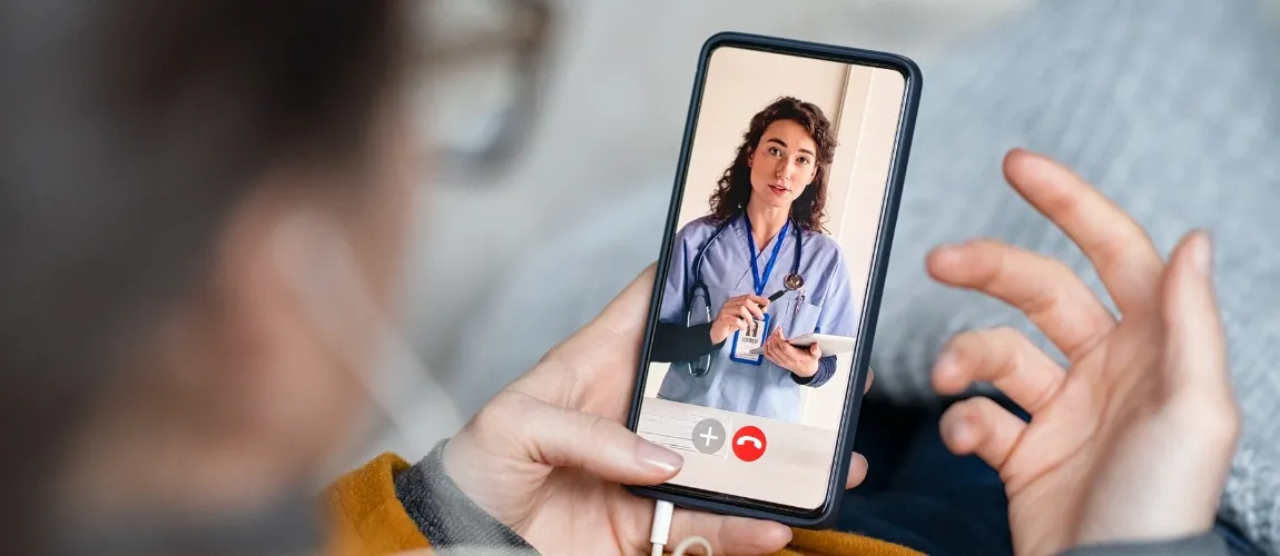 Patientin nimmt an einer digitalen Sprechstunde mit Ärztin über Handy teil.