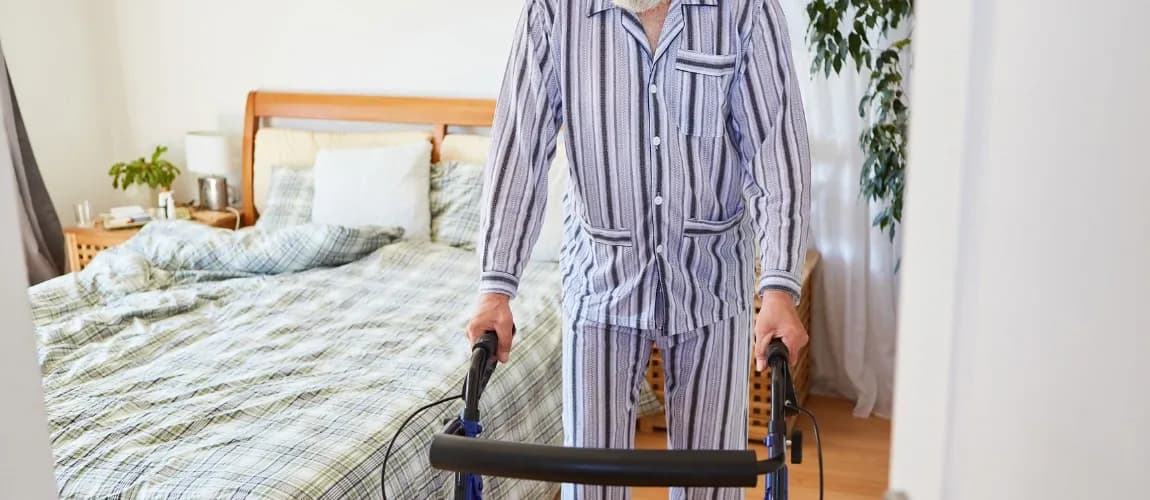 Rollator hilft Senior bei der Sturzprophylaxe im eigenen Schlafzimmer.
