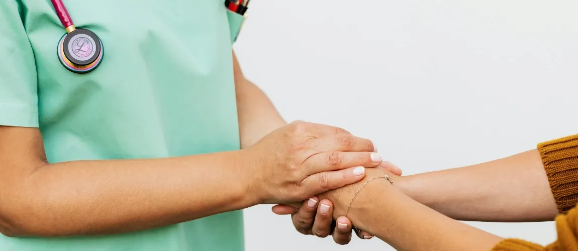 Pflegekraft hält Hand der Patientin.