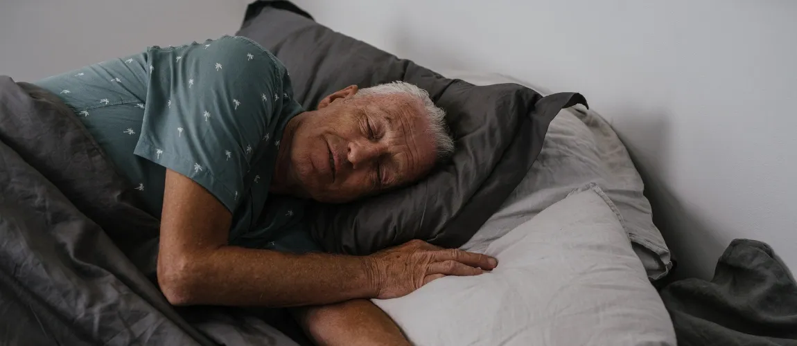 Ein Mann in einem grünen Schlafanzug liegt im Bett und schläft.