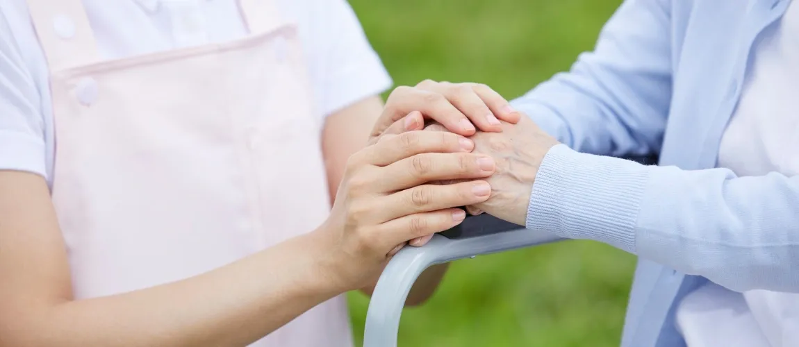 Eine Person hält die Hände einer anderen auf einer Lehne.