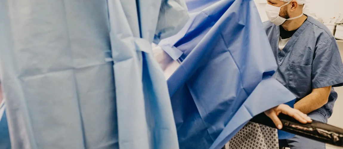 Abbildung einer medizinischen Umgebung, ein Patient ist mit Tüchern abgedeckt.