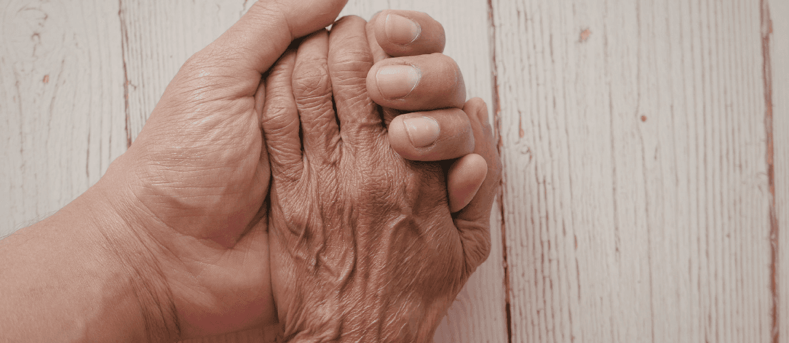 Eine jüngere Frau hält die Hand einer älteren Frau.
