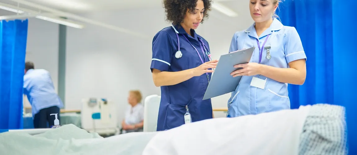 Es sind zwei Krankenschwestern an einem Bett zu sehen.
