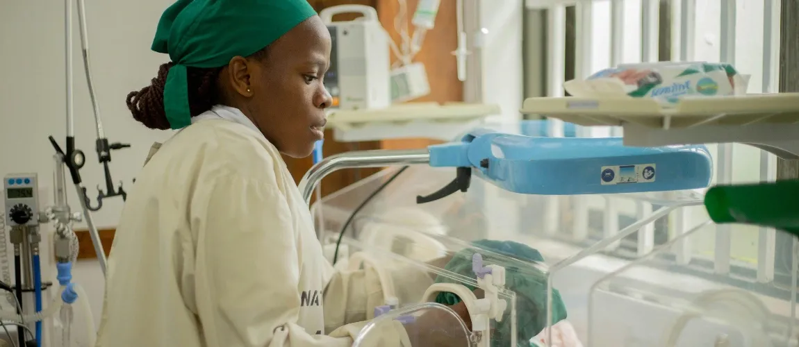 Eine Frau greift mit beiden Händen in einen Inkubator.