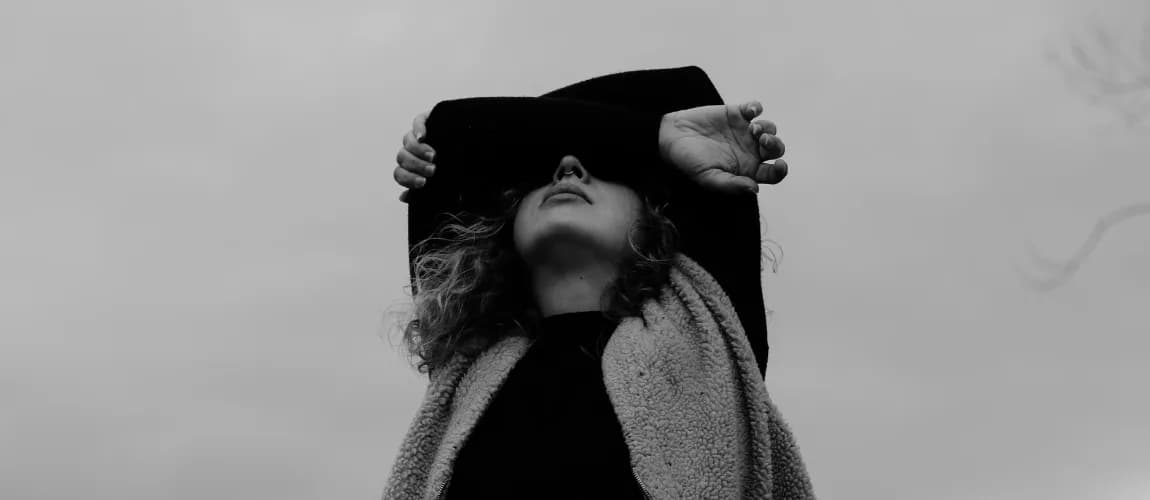 Eine Frau verschränkt die Arme vor dem Gesicht.