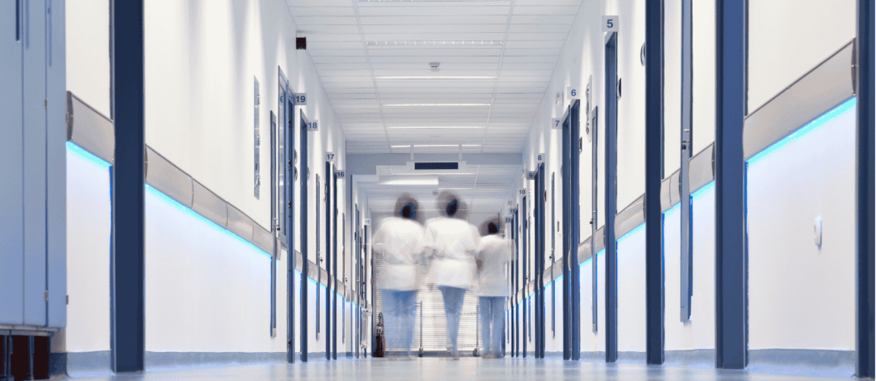 Drei Pflegerinnen laufen Krankenhausgang entland