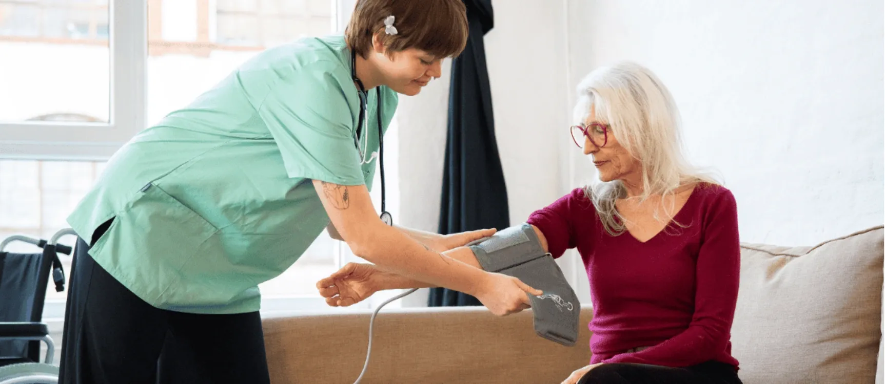 Pfleghelferin legt Patientin Blutdruckmessgerät an