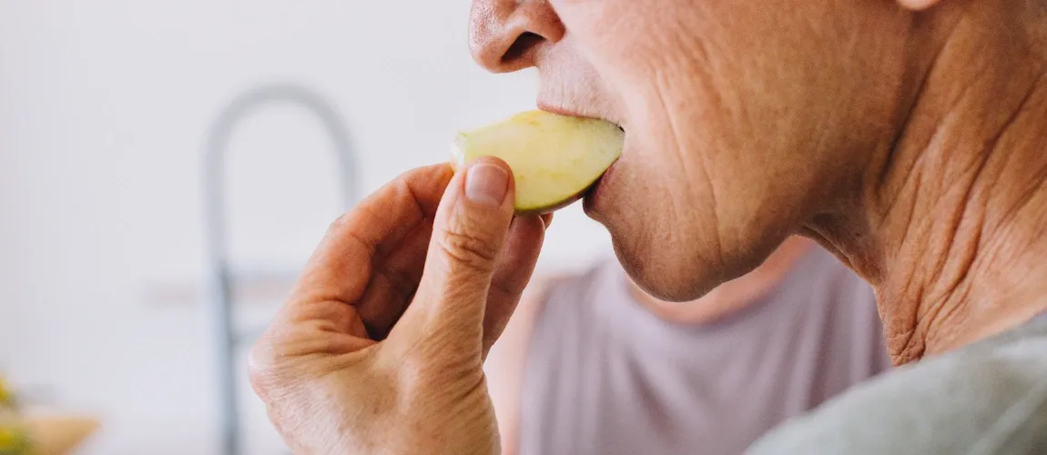 Älterer Mann isst ein Stück Apfel