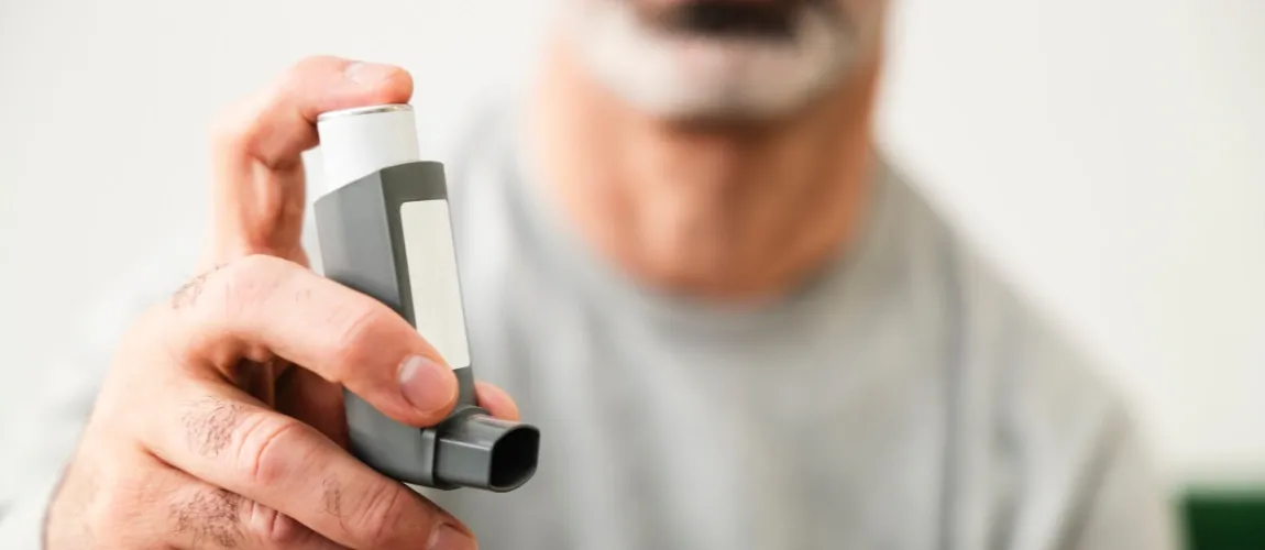 Ein Mann hält eine Asthma-Inhalator in der Hand. 