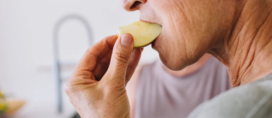 Senior isst ein Stück Apfel