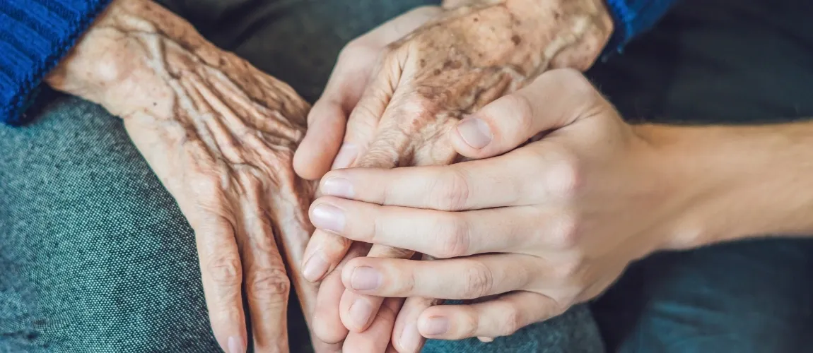 Pflegefachperson hält die Hand einer älteren Dame