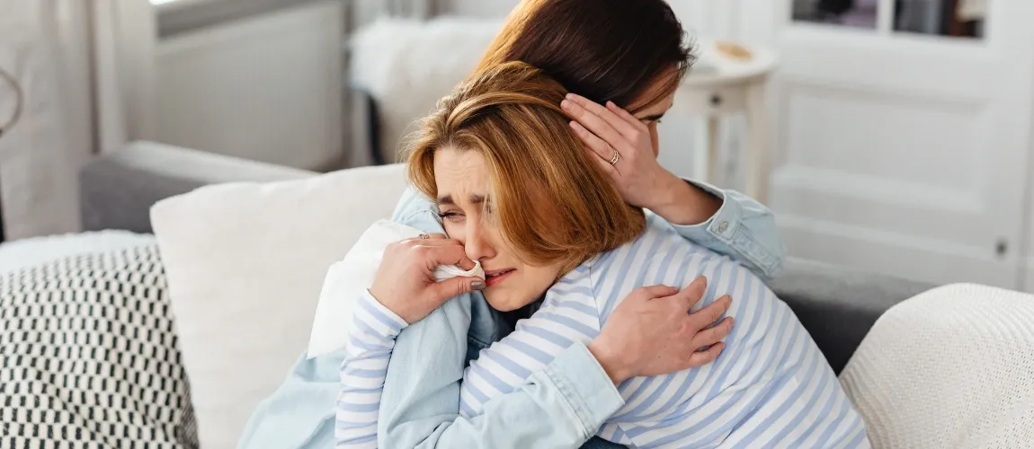 Eine Frau liegt einer anderen Frau weinend in den Armen.