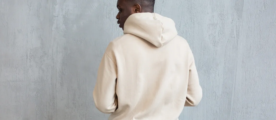 Ein Mann in einem weißen Pullover steht mit dem Rücken zur Kamera.