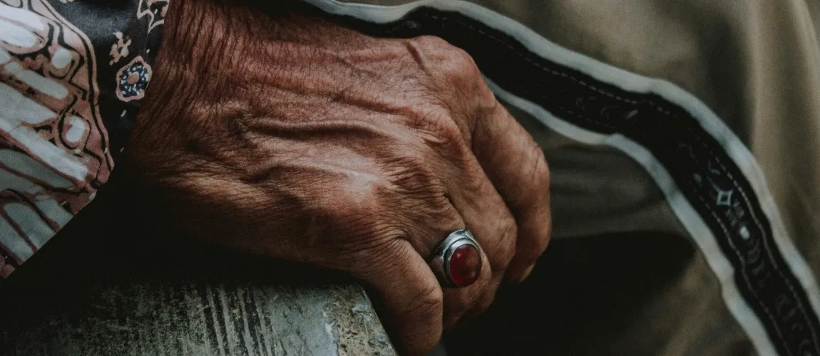 Nahaufnahme von Händen, die neben dem Bein abgelegt sind.