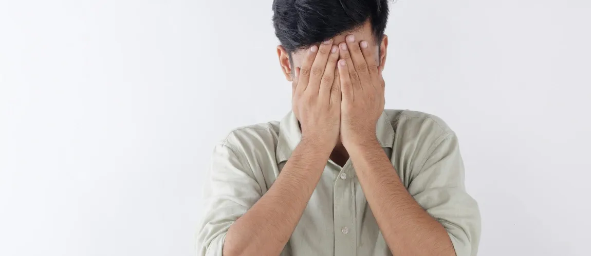 Ein Mann hält sich die Hände vor das Gesicht.