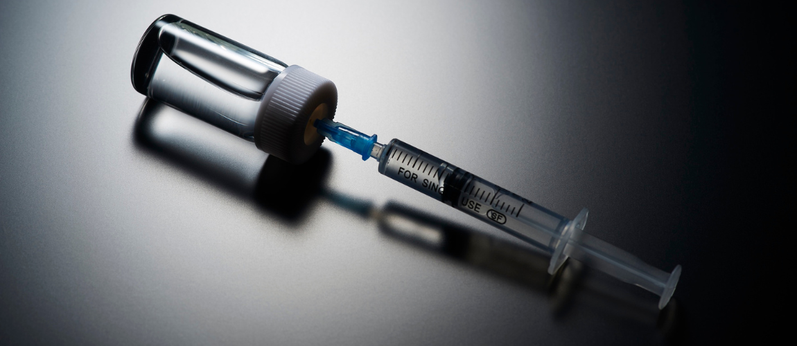 Abbildung einer Spritze, die in einem Behälter steckt. 