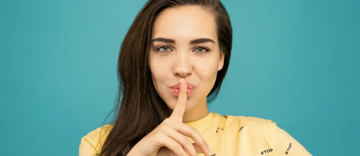 Eine junge Frau hält sich den Finger vor den Mund.