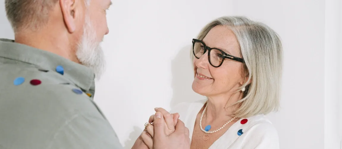 Eine Frau steht einem Mann gegenüber und hält lächelnd seine Hand.