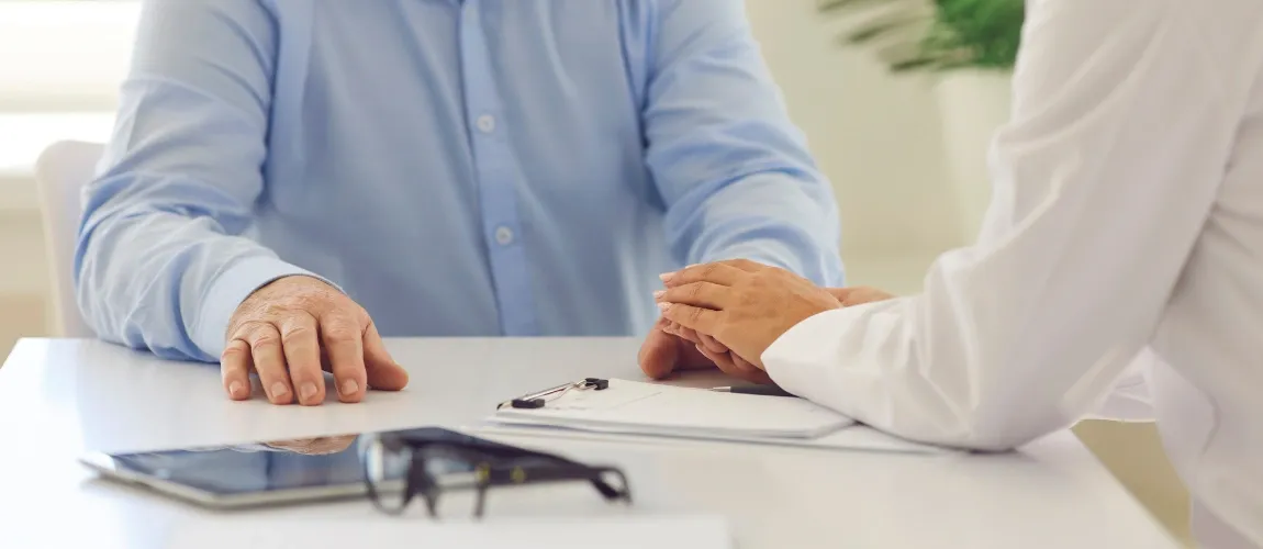 Ein Ärztin legt die Hand auf die eines Patienten.